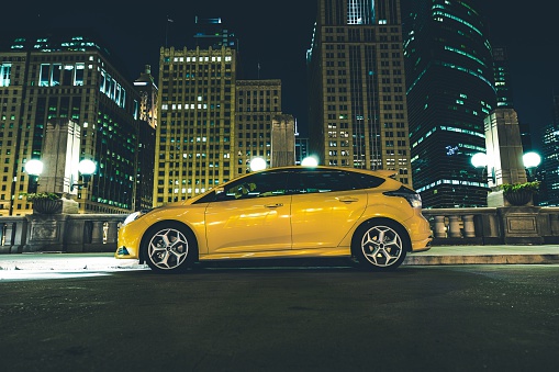 Downtown Parked Car at Night. Downtown Chicago Parking Space. Five Doors Yellow Car with Lights On.